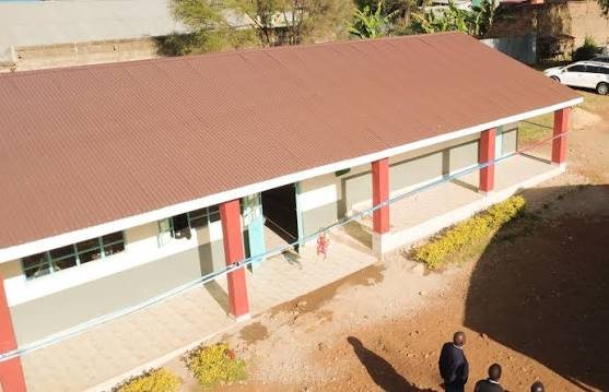 Exterior of a completed community classroom block with a red iron-sheet roof