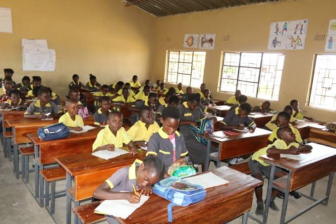 Pupils in school uniform seated at wooden desks in a classroom